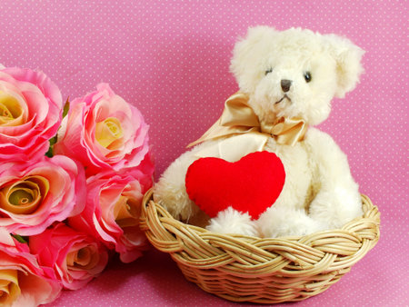 teddy bear with red heart in the basket with pink backgroundの写真素材