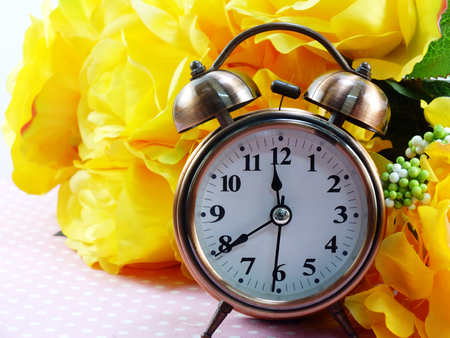spring time with alarm clock and artificial flowers bouquet backgroundの写真素材
