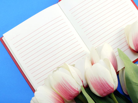 open notebook and beautiful pink tulip artificial flowers bouquetの写真素材