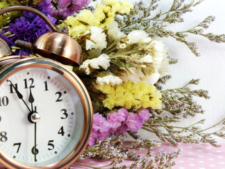 spring time with alarm clock and statice flowers bouquet backgroundの写真素材