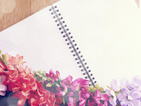 blank notebook diary with pink flower on wooden background made with vintage filters color