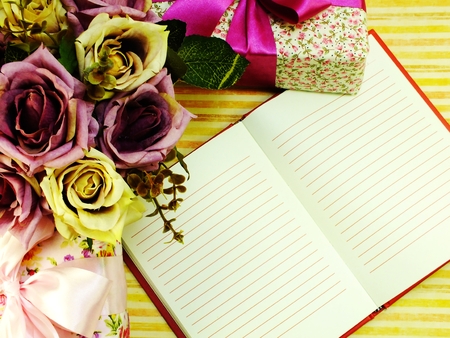 top view of blank sheet of notebook with gift box and beautiful bouquet flowersの写真素材