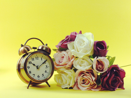alarm clock and artificial flowers bouquet with space backgroundの写真素材