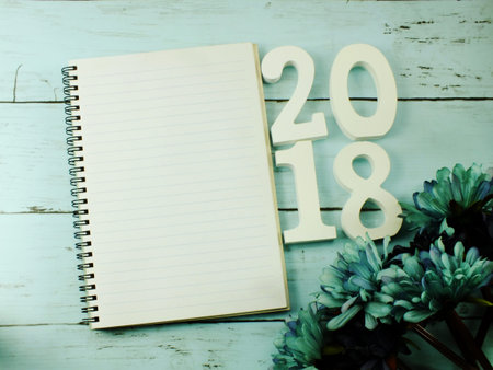 number wooden new year on blank paper notebook on wooden background