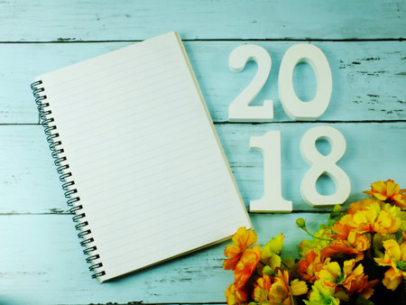 number wooden new year on blank paper notebook on wooden background