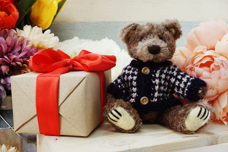 Teddy bear and gift box with red ribbon on wooden backgroundの写真素材