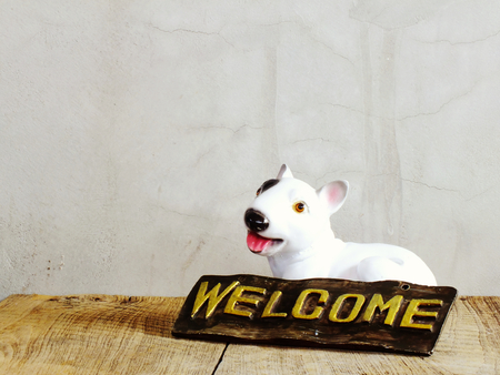 Ceramic dog with welcome sign on wooden backgroundの写真素材