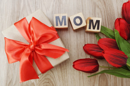 mom with gift box present and flower bouquet on wooden backgroundの写真素材