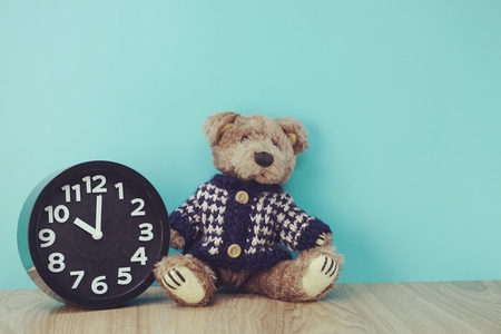 teddy bear and alarm clock with space copy on wooden backgroundの写真素材