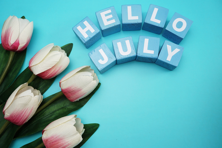 hello july with artificial pink tulip flower on blue backgroundの写真素材