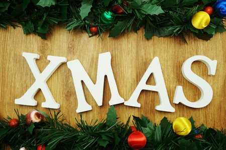 Christmas theme XMAS letter with pine cones and green fir on wooden backgroundの写真素材