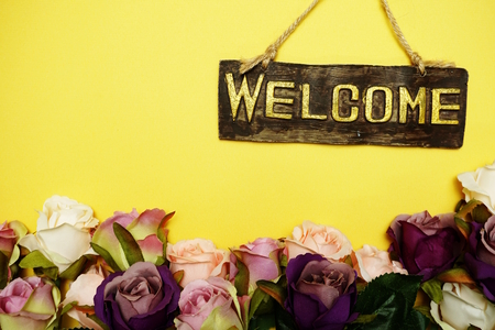 welcome sign with rose flower on yellow backgroundの写真素材