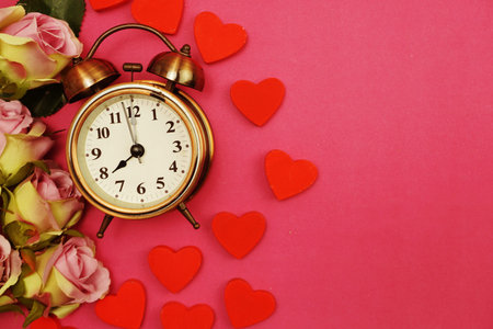 Rose flowers bouquet and vintage alarm clock with space copy on Pink background
