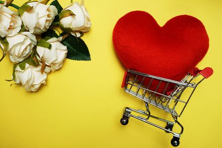 Red Heart and Mini Trolley Shopping Cart on Yellow backgroundの写真素材