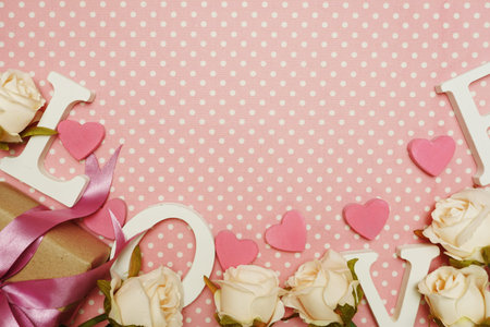 Love word alphabet and Gift box with roses bouquet with space copy on pink polka dot backgroundの写真素材