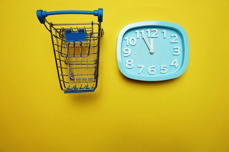 alarm clock and mini trolley cart with space copy on Yellow backgroundの写真素材