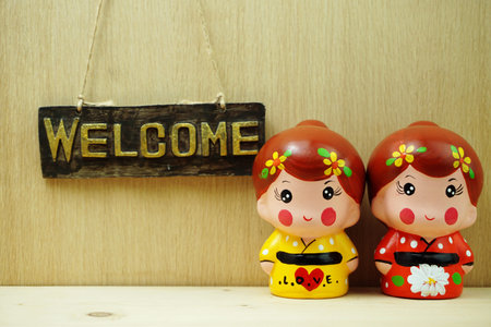 Welcome sign and Ceramic Japanese Girl Doll on wooden background