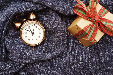 Winter background with alarm clock and gift box on blue knitted cloth texture backgroundの写真素材
