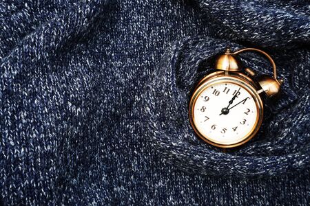 Winter background with alarm clock on blue knitted texture backgroundの写真素材