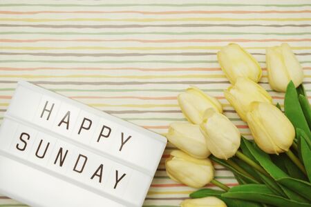 Top view Happy Sunday Text in Light box flat lay with tulip flower bouquetの写真素材