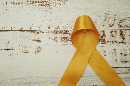 Yellow ribbon cancer awareness on wooden backgroundの写真素材