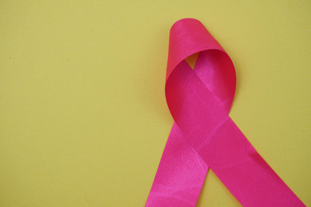 Pink ribbon breast cancer awareness on yellow background