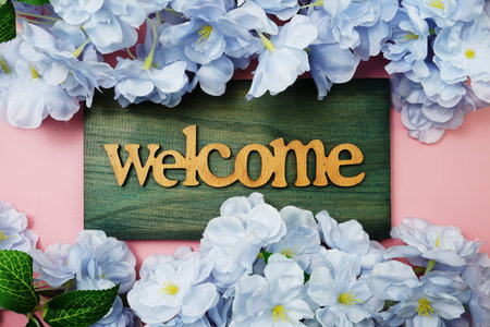 Welcome Sign and Flower Blooming Decoration on pink background