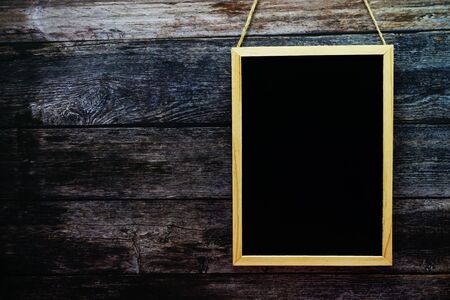 Empty black board on dark wooden wall texture backgroundの写真素材