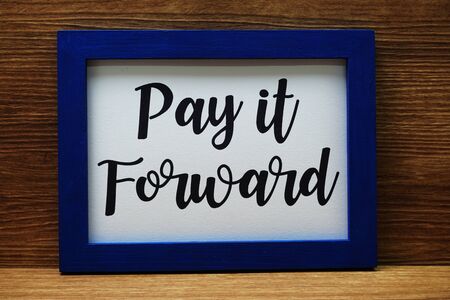 Pay It Forward written with blue photo frame on wooden backgroundの写真素材