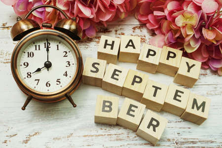 Happy September with alarm clock on wooden backgroundの写真素材