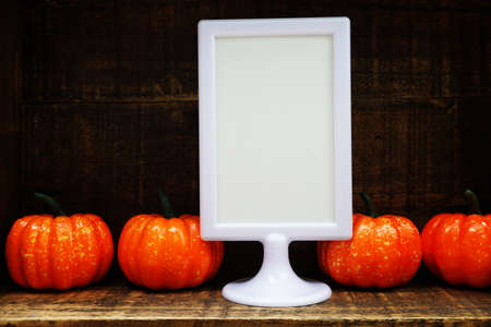 Blank Display frame stand with orange pumpkin on wooden backgroundの写真素材
