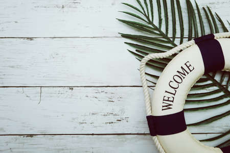 Lifebouy and tropical green leaf on wooden backgroundの写真素材
