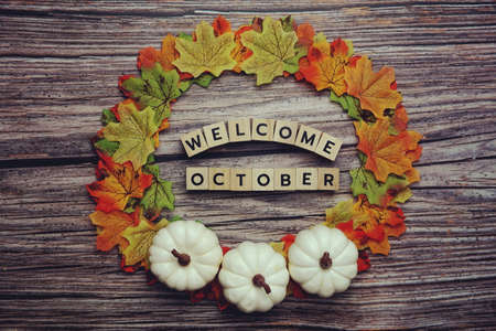 Hello October alphabet letter with pumpkin and maple leaves decoration on wooden backgroundの写真素材