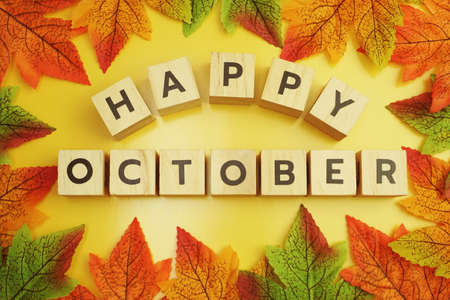 Happy October alphabet letter with maple leaves frame on wooden backgroundの写真素材