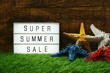 Summer Sale text in light box and starfish on wooden backgroundの写真素材