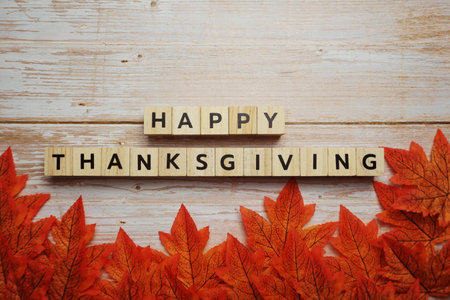 Happy Thanksgiving alphabet letter with autumn leaves on wooden backgroundの写真素材