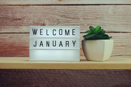 Welcome January word in light box on wooden shelves backgroundの写真素材