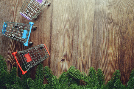Mini Shopping Trolley  with fir tree branches border frame on wooden background