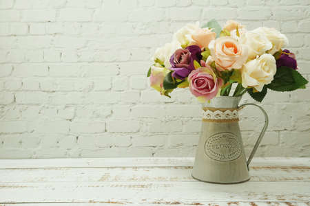 Flowers Bouquet in metal vase home decor on white brick wall and wooden backgroundの写真素材