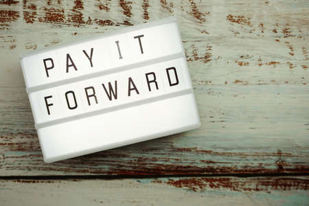 Pay It Forward word in light box with space copy on wooden backgroundの写真素材