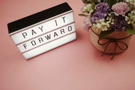 Pay It Forward word in light box with space copy on pink backgroundの写真素材