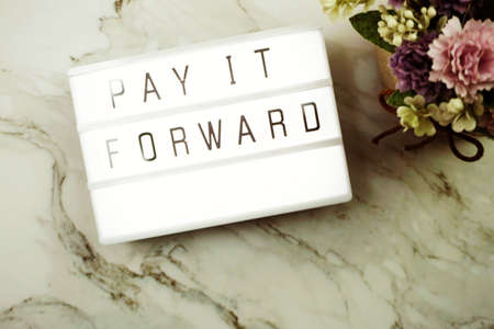Pay It Forward word in light box with space copy on marble backgroundの写真素材