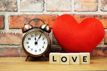 Happy Valentines Day with Love alphabet letter with alarm clock and red heart decoration on brick wall backgroundの写真素材