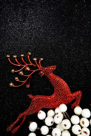 Red Reindeer and white berry Christmas decoration on black glitter backgroundの写真素材