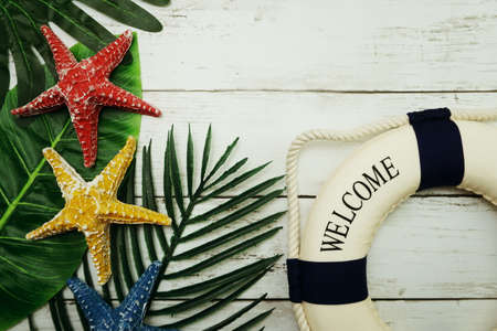 Summer concept with green leave, starfish and lifebuoy decoration on wooden backgroundの写真素材