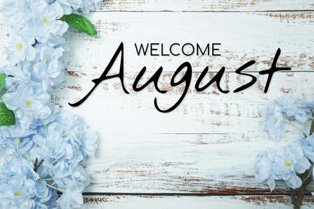 Welcome August text and blue flower decoration on wooden backgroundの写真素材
