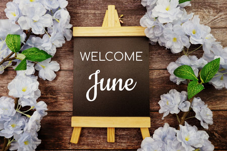 Welcome June text on wooden blackboard and flower decoration on wooden backgroundの写真素材