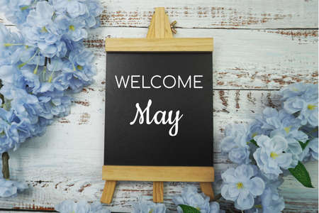 Welcome May text on wooden blackboard and flower decoration on wooden backgroundの写真素材
