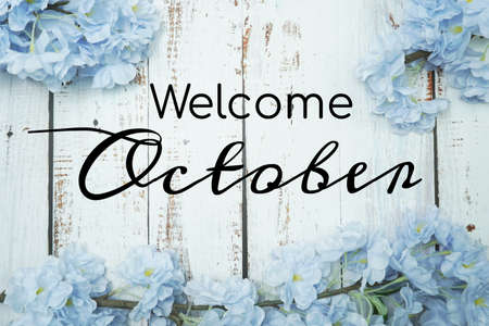 Welcome October text and blue flower decoration on wooden backgroundの写真素材