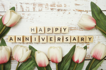 Happy Anniversary alphabet letter with tulip flower bouquet on wooden backgroundの写真素材